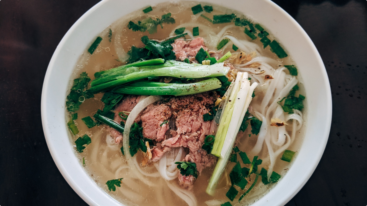 An image of Pho with rice noodel, broth, meat and vegetables in a bowl